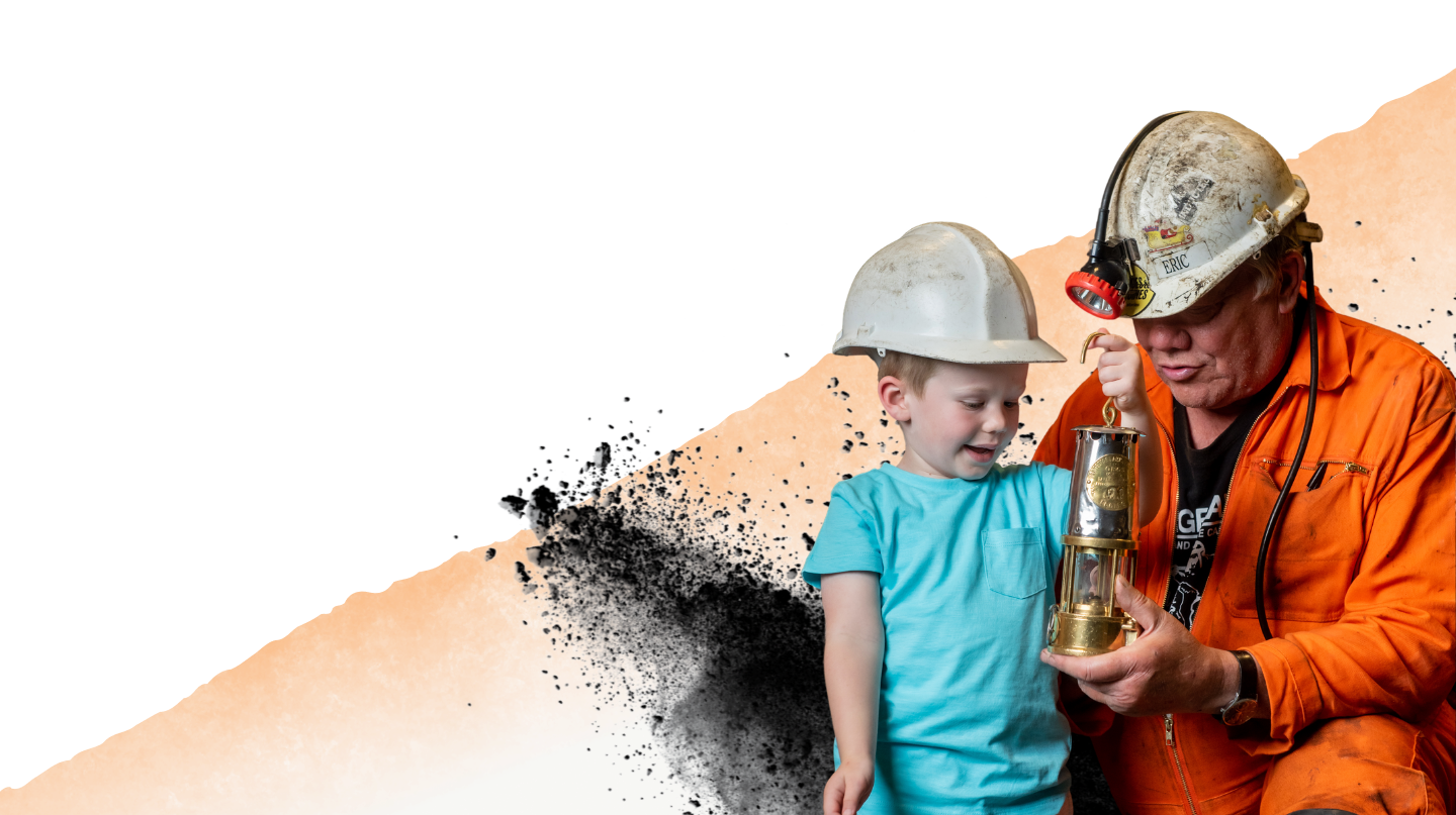 Child and a mine guide looking at a Miner's Lamp up close