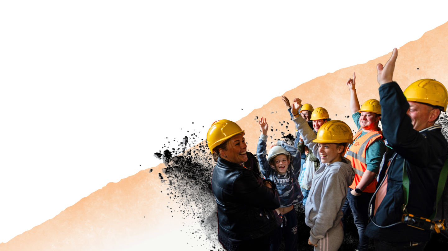 Visitors on a Screens Tour wearing hard hats and raising their arms and laughing